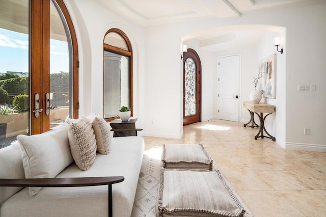 living room with light tile patterned floors, baseboards, arched walkways, and french doors