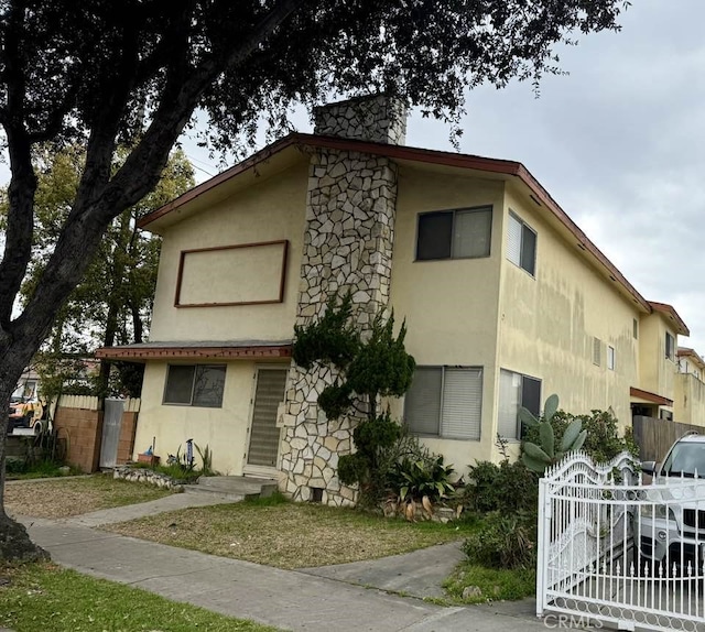 view of front of property with stone siding, fence, and stucco siding