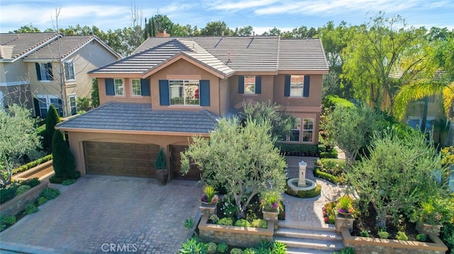 view of front of home featuring an attached garage, decorative driveway, a chimney, and stucco siding