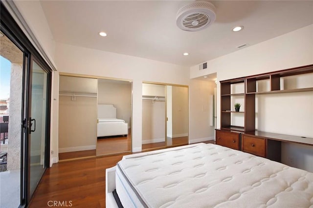 bedroom with baseboards, visible vents, dark wood finished floors, two closets, and recessed lighting