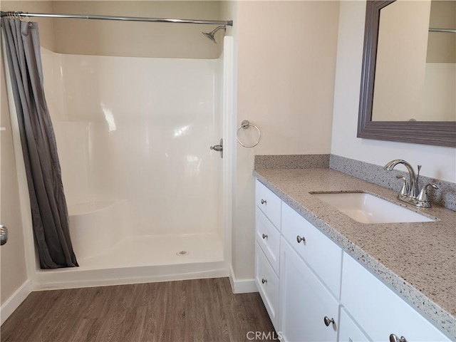 bathroom with vanity, baseboards, wood finished floors, and a stall shower