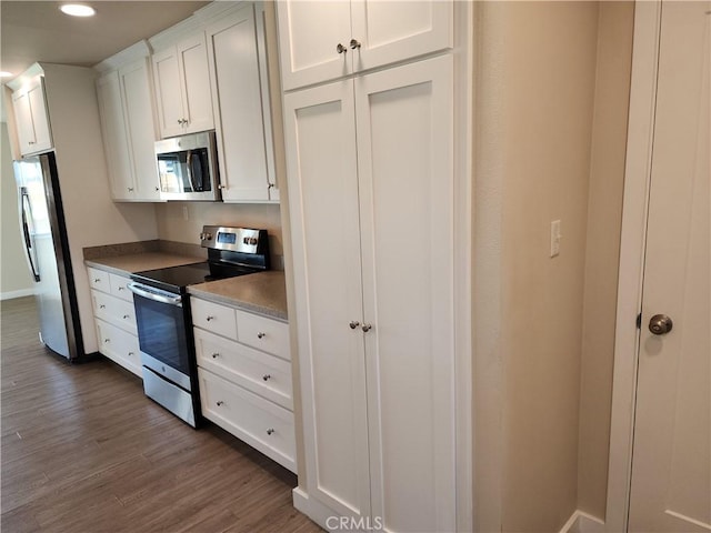 kitchen featuring stainless steel appliances, recessed lighting, white cabinetry, and dark wood-type flooring