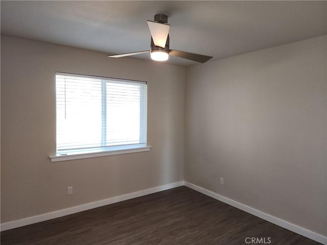 unfurnished room featuring baseboards, ceiling fan, and dark wood-style floors