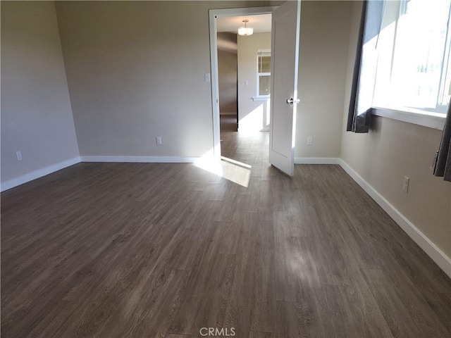 spare room with baseboards and dark wood finished floors