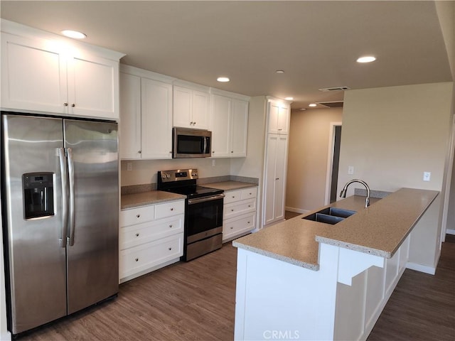 kitchen with a sink, appliances with stainless steel finishes, white cabinets, and dark wood-style floors