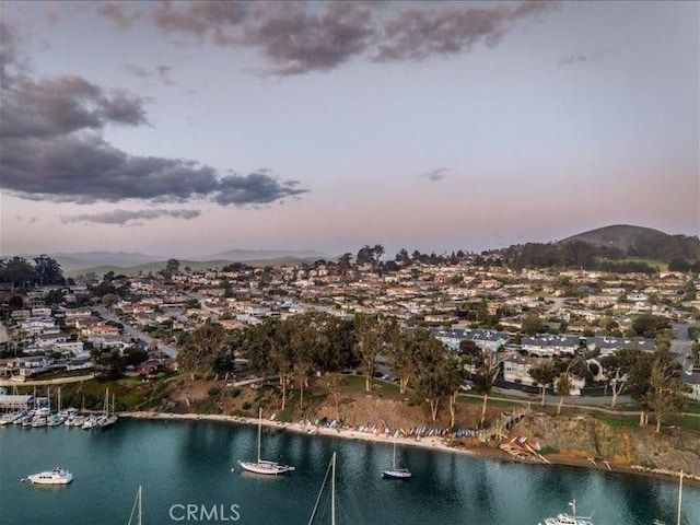 aerial view at dusk featuring a water and mountain view