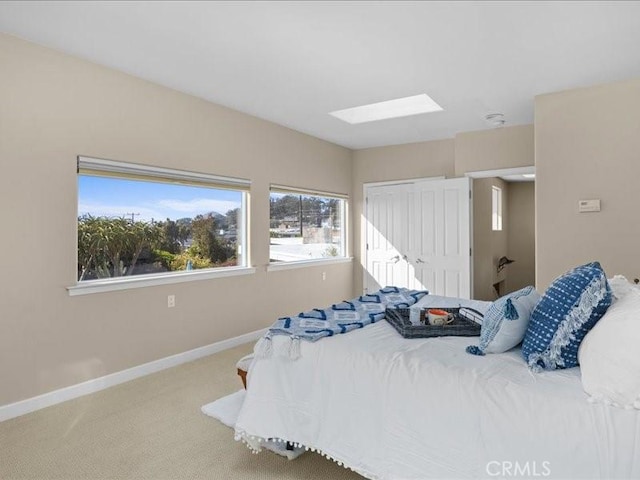 bedroom with a skylight, a closet, baseboards, and carpet floors