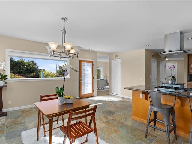 dining area featuring stone finish flooring, baseboards, and a chandelier