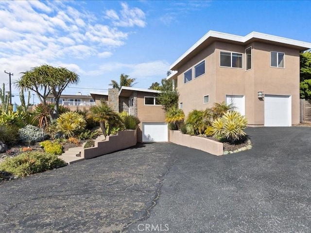 view of front of home featuring aphalt driveway, a garage, and stucco siding