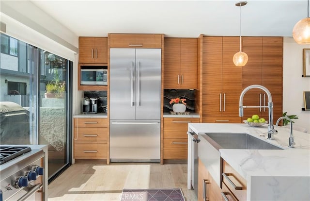 kitchen featuring hanging light fixtures, light wood-style flooring, modern cabinets, and premium appliances