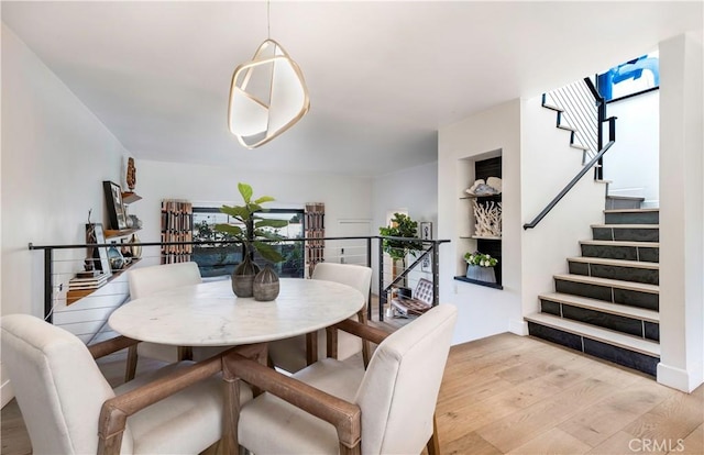 dining space with light wood finished floors, stairway, and built in features