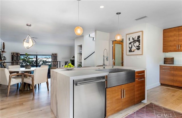 kitchen with light countertops, stainless steel dishwasher, brown cabinetry, and visible vents