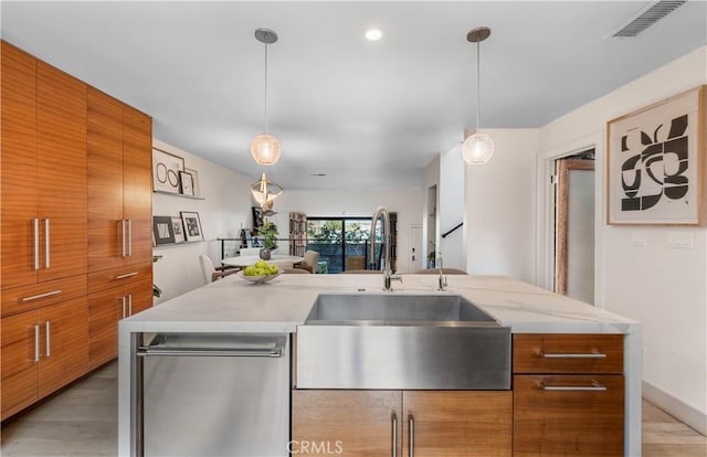 kitchen with visible vents, modern cabinets, brown cabinets, light countertops, and a sink