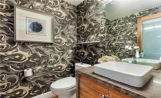 bathroom featuring vanity, toilet, and wallpapered walls