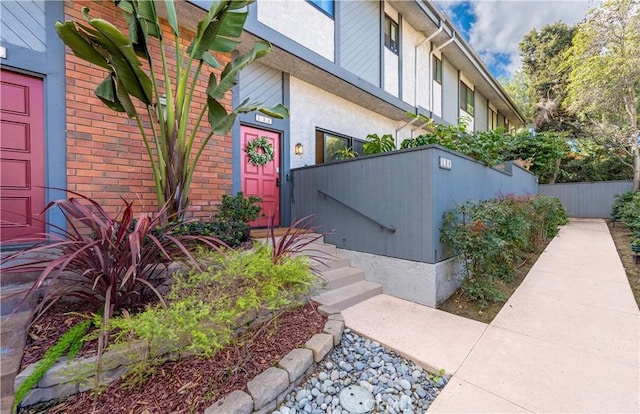 entrance to property with fence and stucco siding