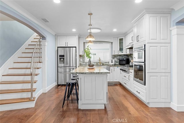 kitchen with a center island, tasteful backsplash, visible vents, appliances with stainless steel finishes, and wood finished floors