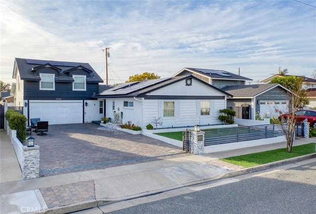 traditional-style home featuring a fenced front yard, decorative driveway, an attached garage, and solar panels