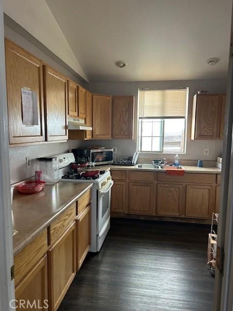 kitchen with lofted ceiling, light countertops, stainless steel microwave, under cabinet range hood, and white gas range oven