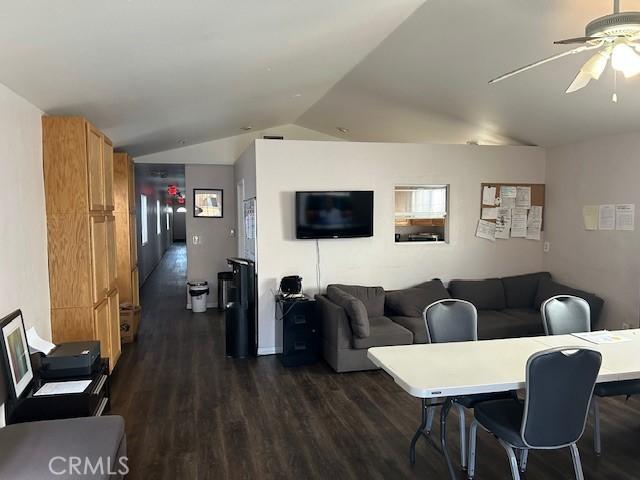 living room featuring ceiling fan, vaulted ceiling, and dark wood finished floors