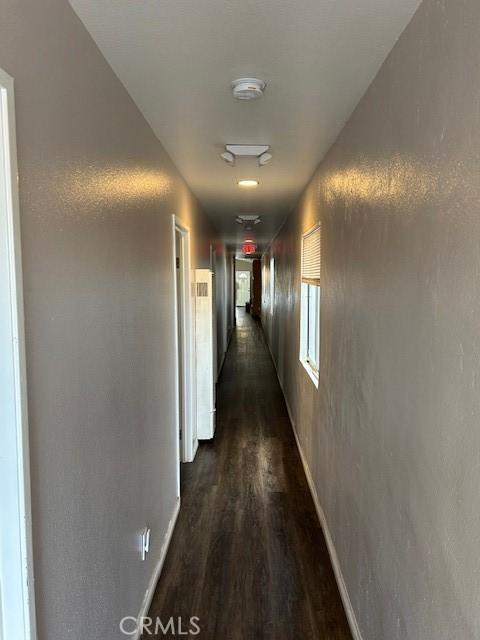 corridor featuring dark wood-style flooring and baseboards