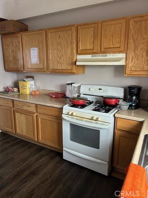 kitchen featuring under cabinet range hood, white range with gas cooktop, light countertops, and dark wood-style flooring