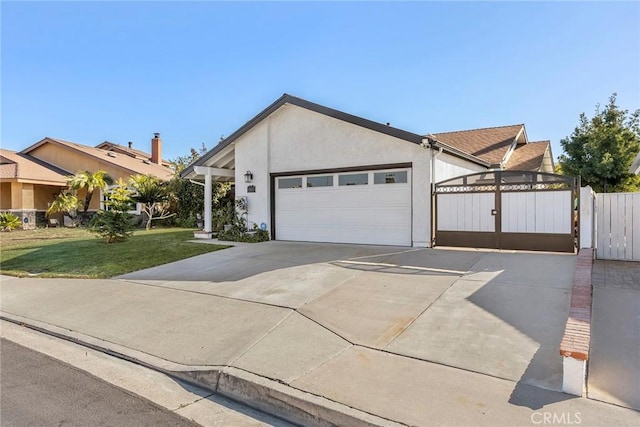 view of front of house featuring a garage, concrete driveway, stucco siding, a gate, and a front yard