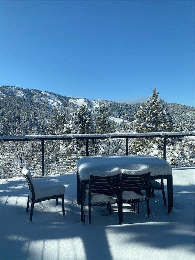 snow covered back of property featuring a mountain view