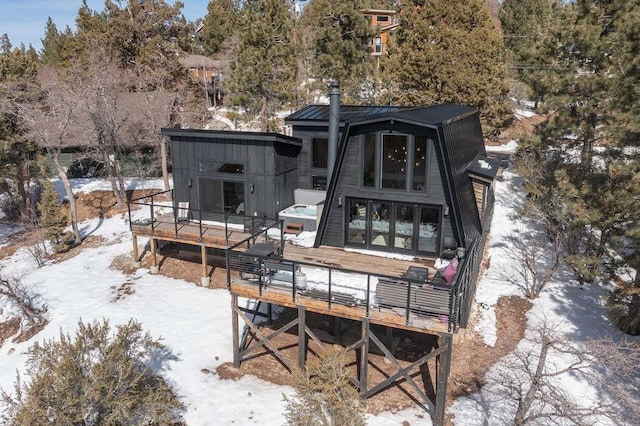 snow covered rear of property featuring metal roof, a standing seam roof, and a wooden deck