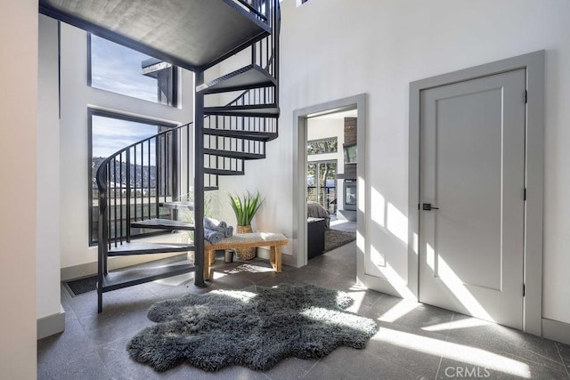 entryway featuring baseboards, a high ceiling, and stairway