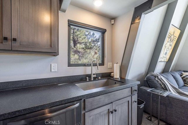 kitchen featuring stainless steel dishwasher, dark countertops, and a sink