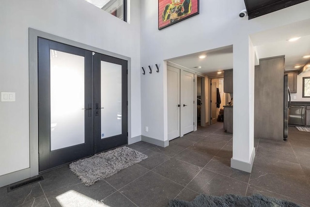 foyer entrance featuring french doors, a high ceiling, visible vents, and baseboards