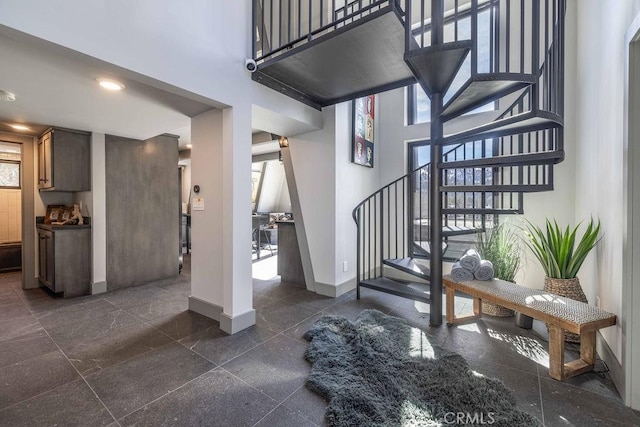 stairway featuring recessed lighting, a towering ceiling, and baseboards