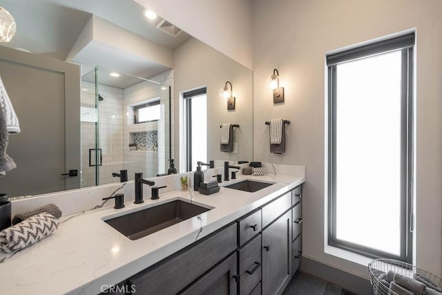 bathroom with double vanity, a shower stall, visible vents, and a sink