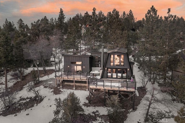 back of property at dusk with board and batten siding and a deck