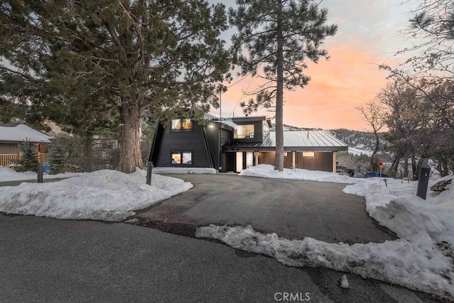 view of front of property featuring metal roof, driveway, and a standing seam roof