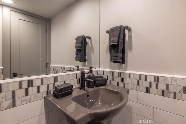 bathroom featuring wainscoting, a sink, and tile walls