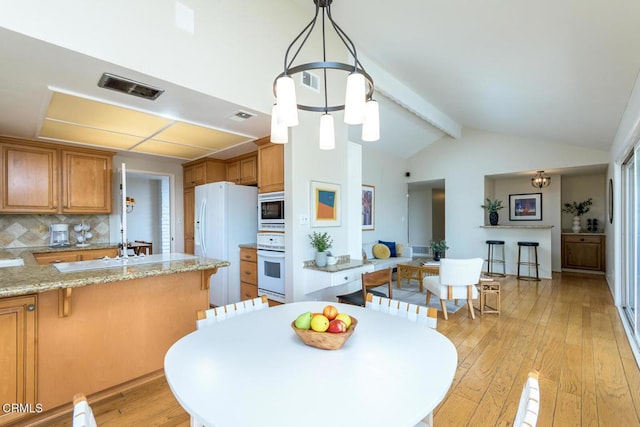 dining area with visible vents, vaulted ceiling with beams, and light wood finished floors