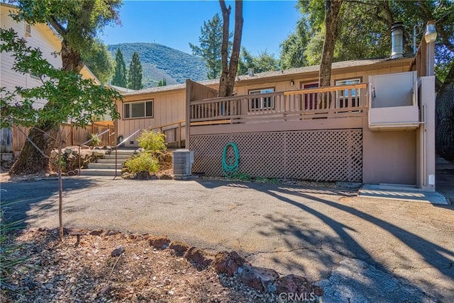 view of front of home featuring a deck with mountain view, cooling unit, and fence