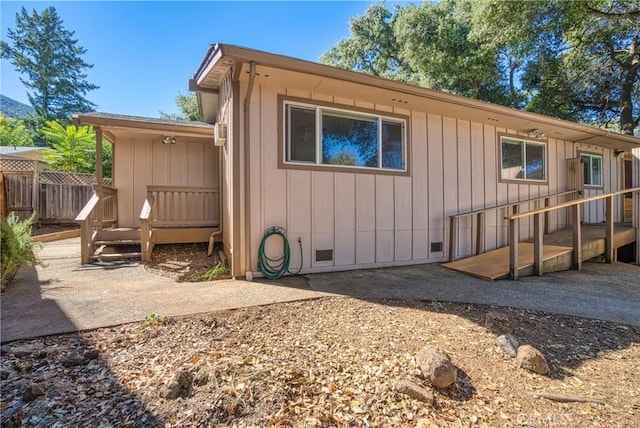 exterior space featuring crawl space, fence, board and batten siding, and a patio