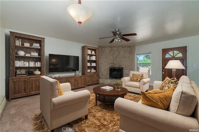 living area featuring carpet, a fireplace, a ceiling fan, and built in features