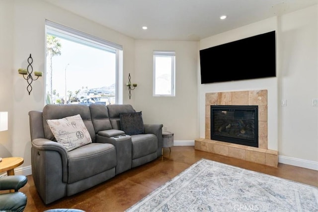 living area with baseboards, a tiled fireplace, and recessed lighting