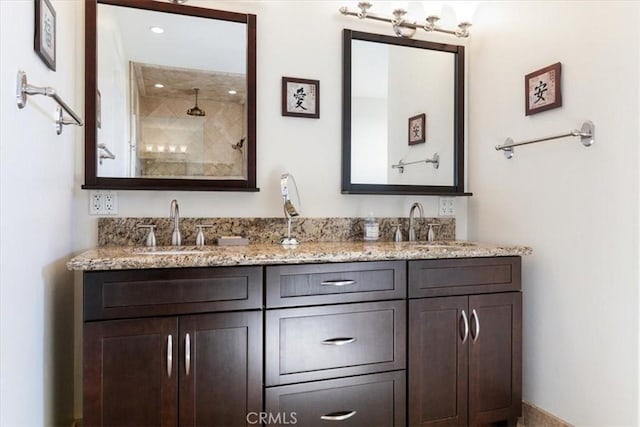 full bathroom with a sink, a tile shower, and double vanity
