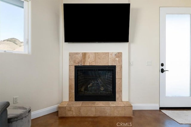 details with a fireplace, finished concrete flooring, and baseboards