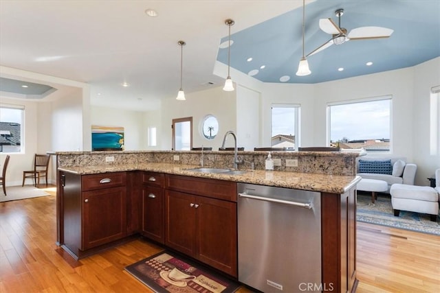 kitchen featuring open floor plan, dishwasher, light wood-style flooring, and a sink
