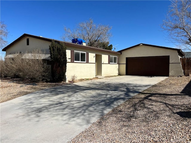 ranch-style home featuring a garage, concrete driveway, and stucco siding