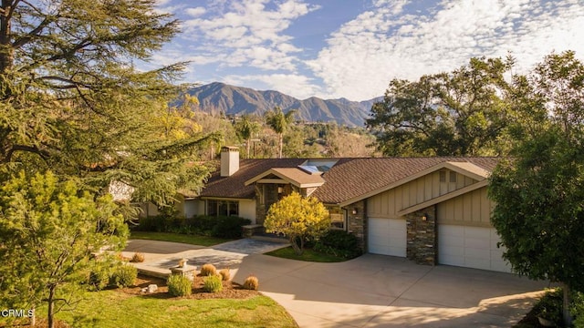 view of front of home with concrete driveway, board and batten siding, an attached garage, and a mountain view