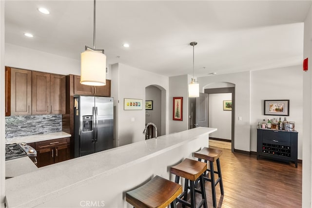 kitchen featuring light countertops, pendant lighting, stainless steel fridge, and arched walkways