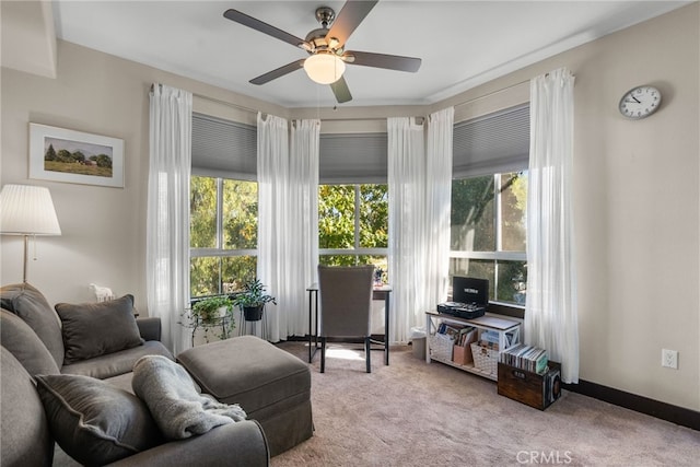 living room featuring baseboards, a ceiling fan, a wealth of natural light, and light colored carpet