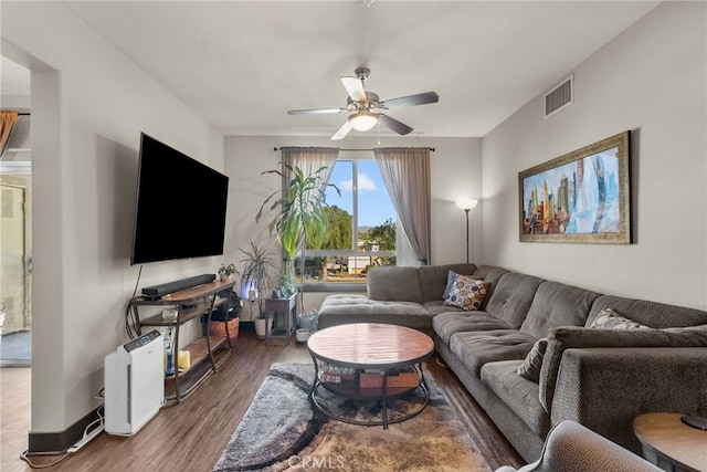 living room with baseboards, dark wood-style flooring, visible vents, and a ceiling fan