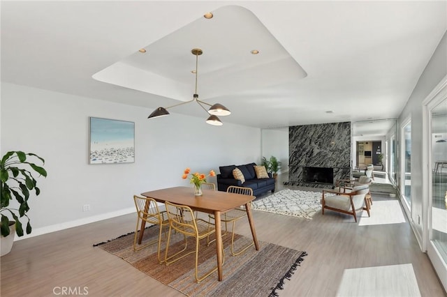 dining area featuring a premium fireplace, a tray ceiling, and wood finished floors